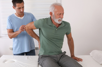 Senior man with back pain. Spine physical therapist and paient. Chiropractic pain relief therapy.
